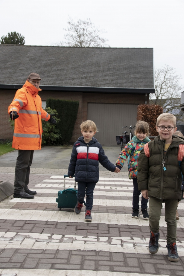 Gemachtigd opzichter helpt kinderen oversteken aan de schoolpoort